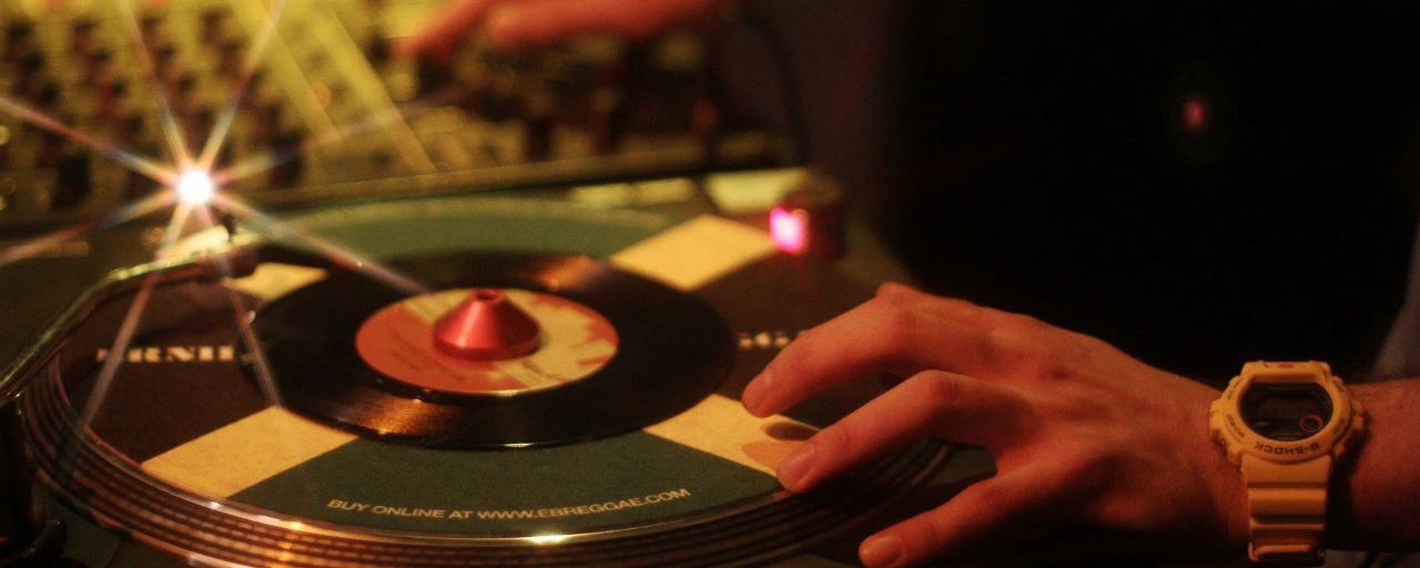 Hand on a spinning vinyl record in warm club light